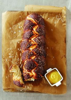 a loaf of bread sitting on top of a piece of wax paper next to a container of mustard