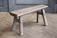 a wooden bench sitting on top of a tile floor next to a door and wall