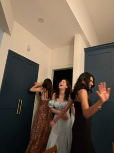 three women standing in a room with blue doors