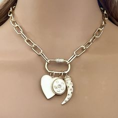 This necklace features a chunky open link paperclip  chain with 14k gold plating. The chain is electroplated for extra durability. Three gorgeous charms attached. The Charms hang on a gold plated carabiner screw clasp and are removable.  1.White enamel Heart Charm. 2.White enamel Oval charm with CZ center stone. 3.White enamel tusk with green, red and clear CZ stones Available in many lengths. Please choose length from drop down menu Tips to keep your jewelry looking good. 1) Keep jewelry away from water and chemicals. 2) Remove during physical activities. 3) Store separately in a soft pouch or airtight box. 4) Avoid wearing to bed. 5) Gently polish with a soft, lint-free cloth to clean.FAST SHIPPING! PACKAGING 🎁 All items come beautifully packaged in their own pouch or box. Gift messages Sterling Necklace, Picture Locket, Beautiful Gold Necklaces, Stainless Steel Chain Necklace, 18k Gold Necklace, Trombone, Necklace Online, Necklace Vintage, Keep Jewelry