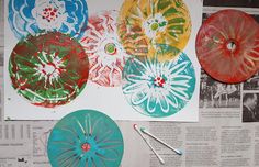 four colorful paper plates sitting on top of a newspaper