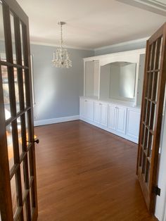 an empty living room with wood floors and white cupboards on either side of the door