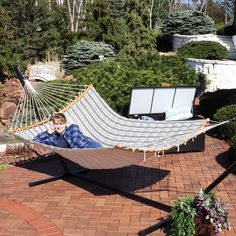 a man laying in a hammock on a brick patio