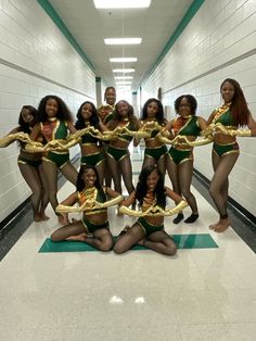 a group of women in green and gold outfits posing for a photo with their arms wrapped around each other