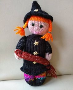 a crocheted doll wearing a black hat and holding a red ribbon in her hand