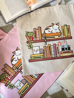 two books are laying on the floor next to an open bookcase with cats sleeping on it