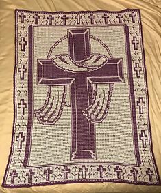 a crocheted blanket with a cross on the front and an embroidered border around it