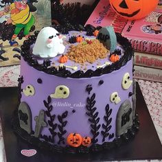 a decorated halloween cake sitting on top of a table next to books and pumpkins