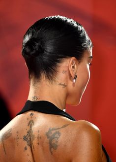 the back of a woman's head with tattoos on her upper and lower body