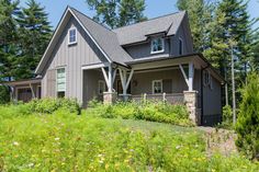 a house in the woods with lots of trees and flowers on the grass around it