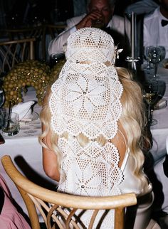 a woman sitting at a table with a white hat on her head