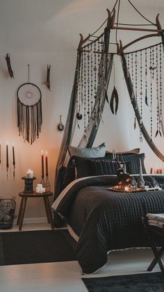 a bedroom decorated in black and white with feathers hanging from the ceiling, candles lit up on the bed