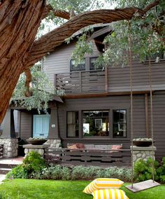 a house with a tree in front of it and a swing set on the lawn