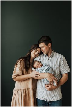 a man and woman holding a baby in their arms