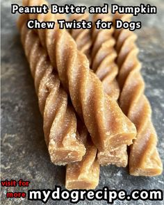 several pieces of peanut butter and pumpkin chew twists for dogs on a gray stone surface