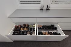 an open drawer in the floor next to a counter with several pairs of shoes on it