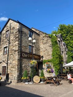 an old stone building with tables and benches in front of it on a sunny day