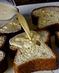 someone pouring butter onto some bread on a white plate with other pieces in the background