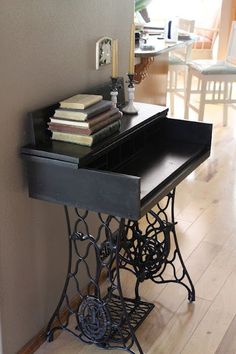 an old sewing machine is sitting on the floor in front of a table with several books