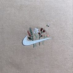 an embroidered sweater with flowers on it and a white nike logo in the middle,