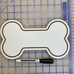 a dog bone sticker with a pen on it next to a ruler and marker