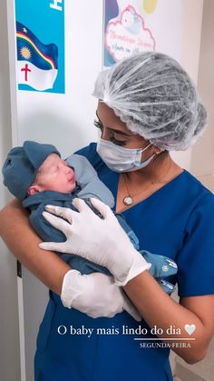 a woman in scrubs holding a baby wearing a surgical mask and gloves on her head