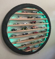 a wall mounted toy car display in a circular black frame with green light behind it