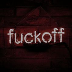 a neon sign that says fuckot hanging on a brick wall