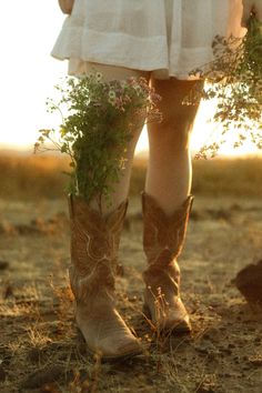 a woman in cowboy boots holding a plant