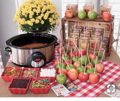 an assortment of apples and candies on a table next to a crock pot