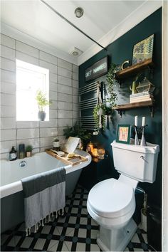 a white toilet sitting in a bathroom next to a bath tub filled with greenery