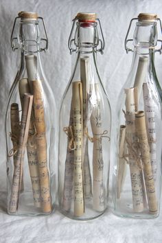 three glass bottles with corks in them and some paper on the bottom one is empty