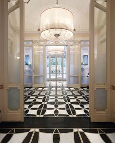 an ornate hallway with chandelier and black and white tiles