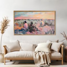 a painting hanging on the wall above a couch in a room with white walls and pillows