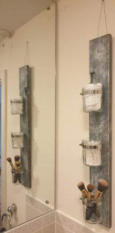 a bathroom mirror with two hanging jars on the wall