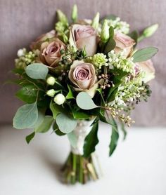 a bouquet of flowers sitting on top of a white table next to a gray couch