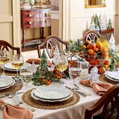 a dining room table set for christmas with plates, glasses and silverware on it