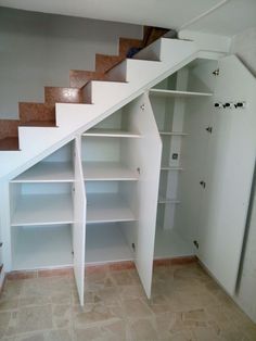 an empty room with some shelves under the stairs