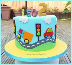 a blue birthday cake with cars and traffic lights on it's side sitting on a table