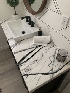 a bathroom vanity with marble counter top and mirror above it, next to a plant