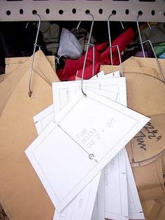 several pieces of paper are hanging on clothes pins in a closet filled with clothing and other items