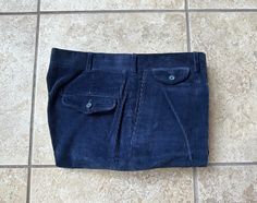 "Here is a pair of vintage corduroy trousers from \"Lands' End.\" They are tagged a size 35, but they measure most like a true-to-size 34 x 28.75; still, please use the measurements provided to ensure a proper fit.  Made in the USA of a cotton/poly blend (88% / 12%) in a corduroy weave, their color is a staple dark blue. They further feature a front hidden hook-and-eye closure and a zipper fly, slanted front pockets and a flapped change pocket, 2 rear pockets (both jetted and one with a button), Fitted Blue Corduroy Bottoms, Fitted Corduroy Bottoms With Welt Pockets, Mens Trousers, Lands End, Online Retail, Blue And Silver, Dark Blue, Zipper, Trousers