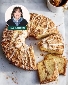 a cake with white icing and cinnamon sprinkles on it next to a cup of coffee