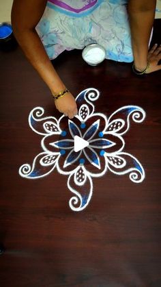 a woman is drawing on the floor with chalk