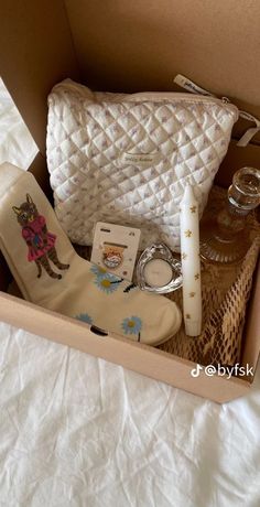 the contents of a white purse are neatly packed in a cardboard box on a bed