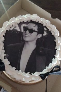 a cake with an image of a woman wearing sunglasses on it in a cardboard box