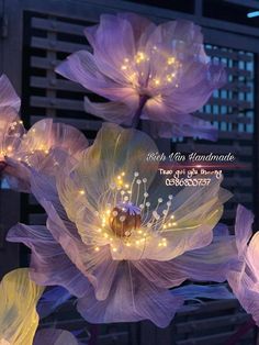 purple flowers with lights on them in front of a building