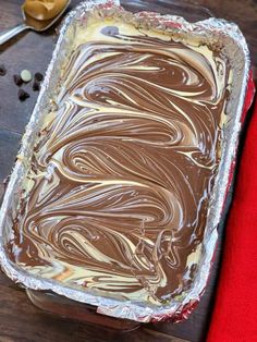 a pan filled with chocolate frosting on top of a wooden table