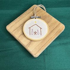 a cross stitch ornament hanging from a wooden frame on a green cloth background