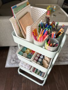 a cart filled with lots of different colored pens and pencils on top of a wooden floor